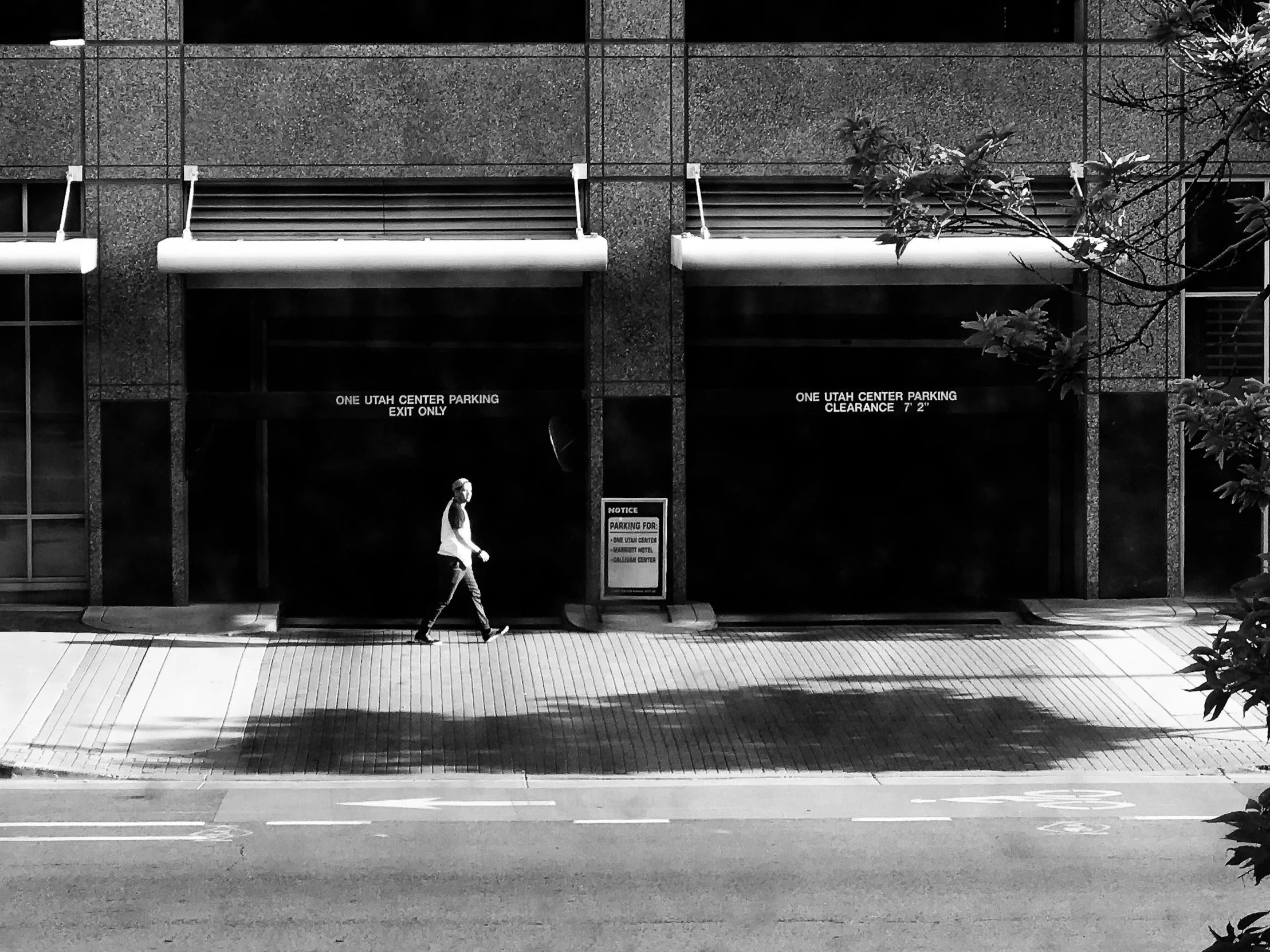 black and white pograph of man walking on the sidewalk