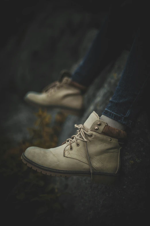 a person wearing light colored shoes is standing on rocks