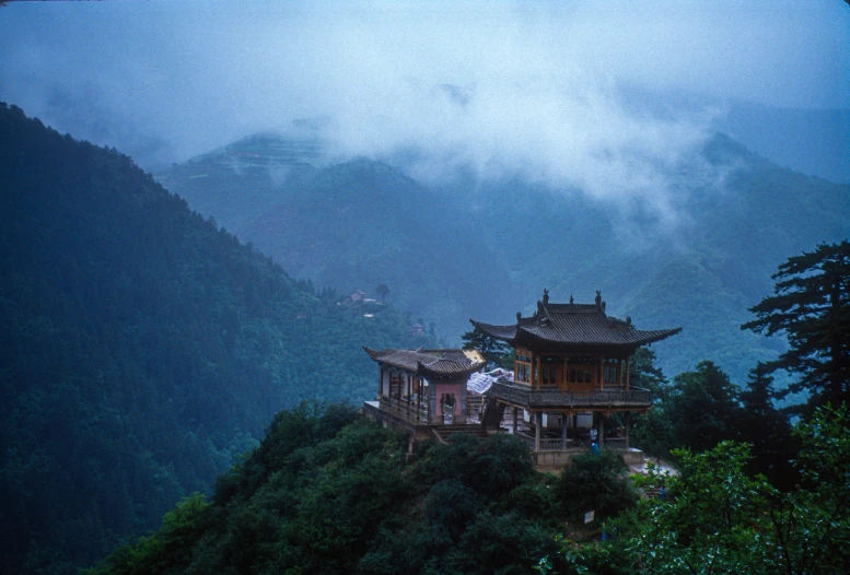 a chinese house sits on the top of a hill surrounded by fog