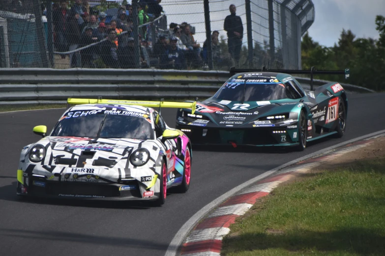 two race cars speeding down a track near some fans