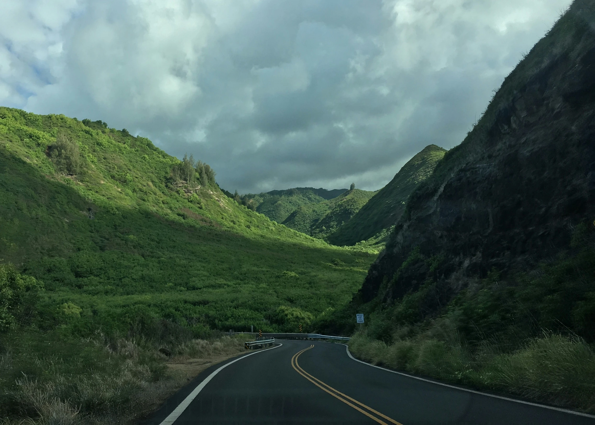 a curve in the road going through lush green hills