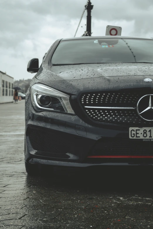 black mercedes parked in the rain by a stop light