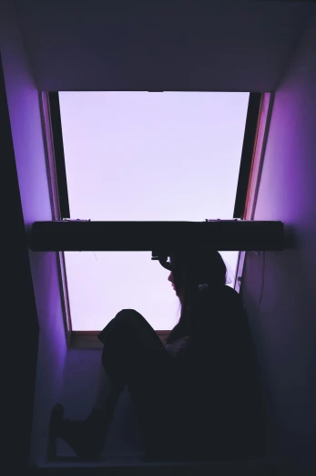 a woman sitting under a window under a light
