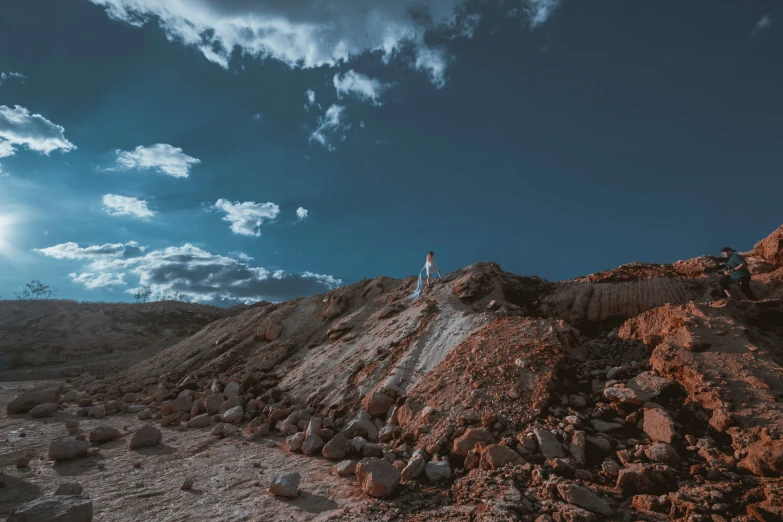 a person standing at the top of a hill with rocks on it