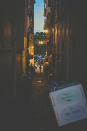 an alleyway with people walking around and cars in the distance