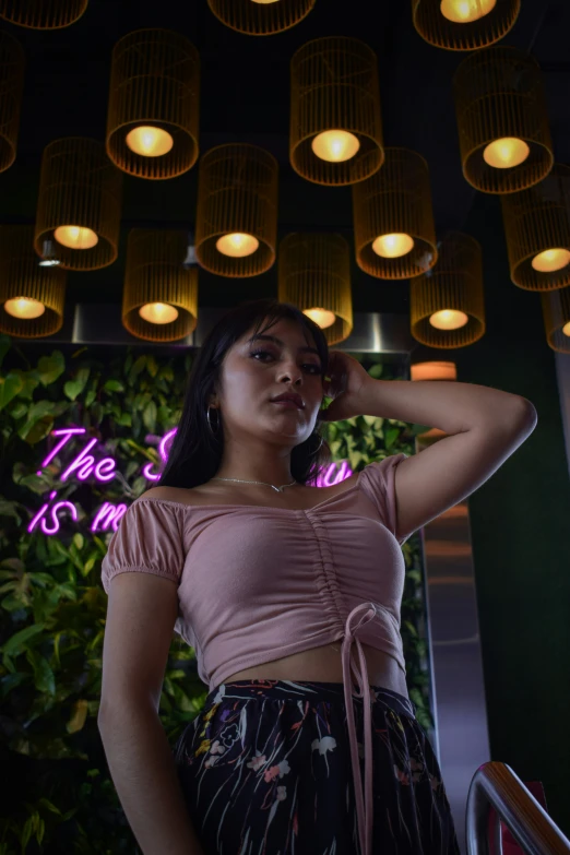 woman in a pink top stands in front of lights