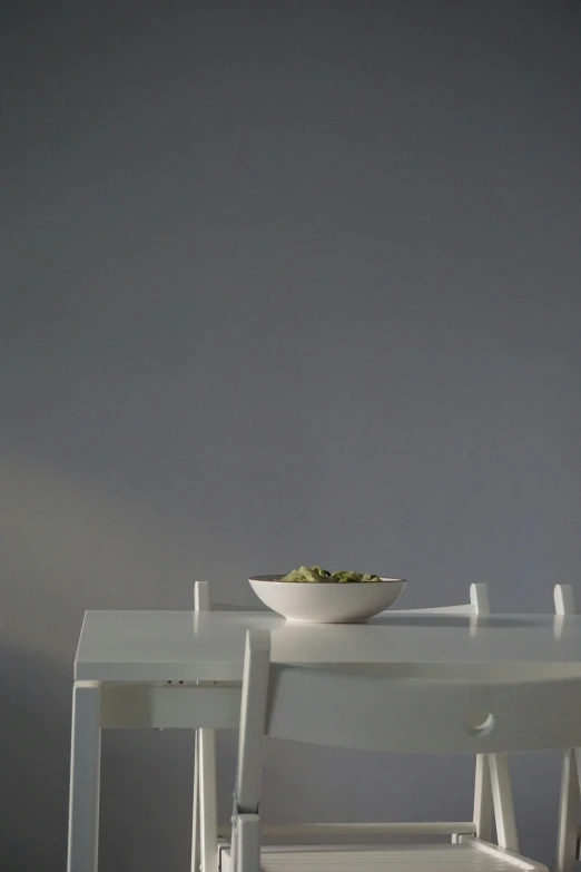 the table and chairs are white with a bowl on top of one