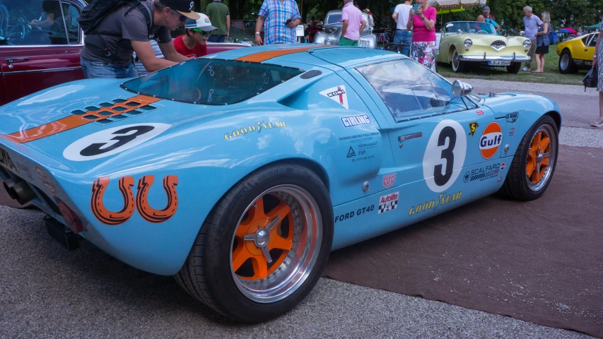 a vintage racing car with orange rims parked on the street