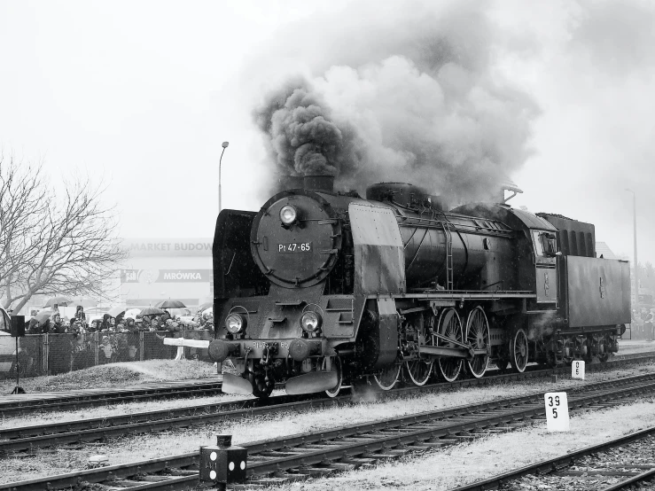 the steam engine is releasing dark smoke as it goes down the tracks