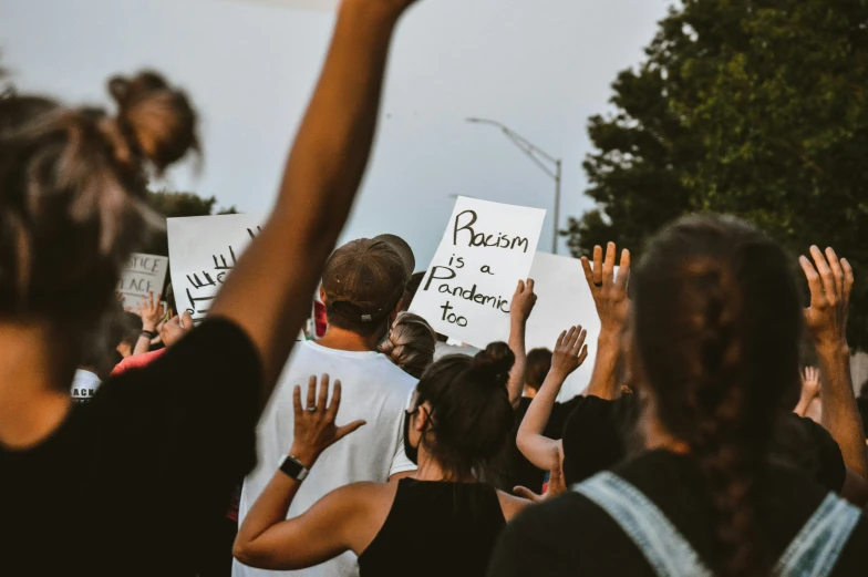 people holding signs at a protest against president donald