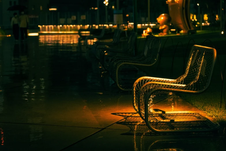 three metal chairs with the light on in a plaza