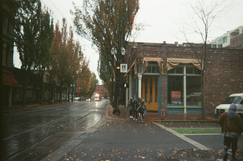 people walking in the rain on a road with trees in the background