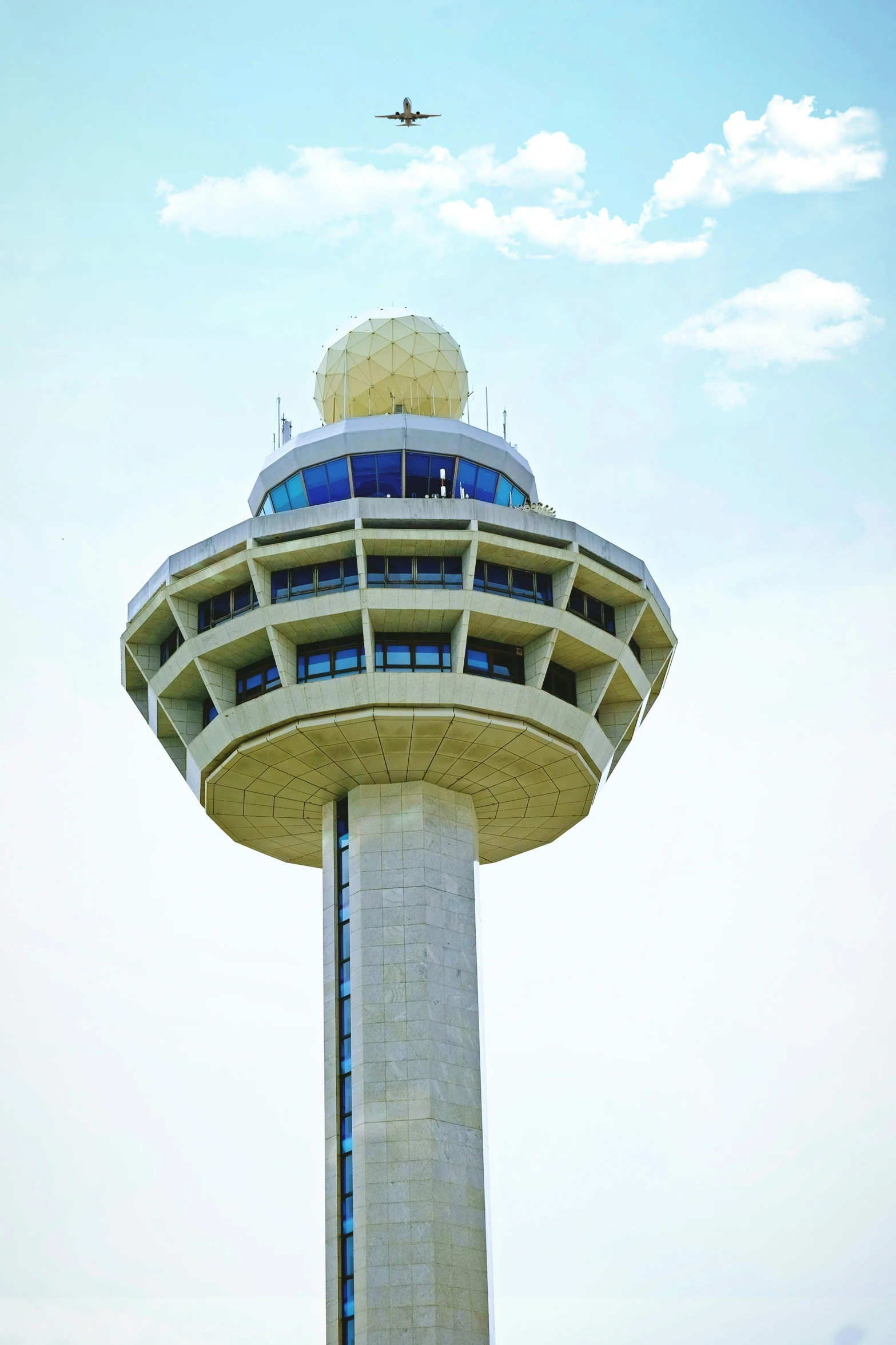 an airplane is flying overhead in the sky next to the tower