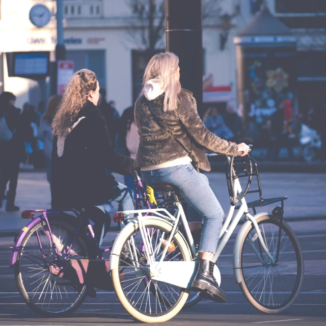 two girls on bicycles standing on the street