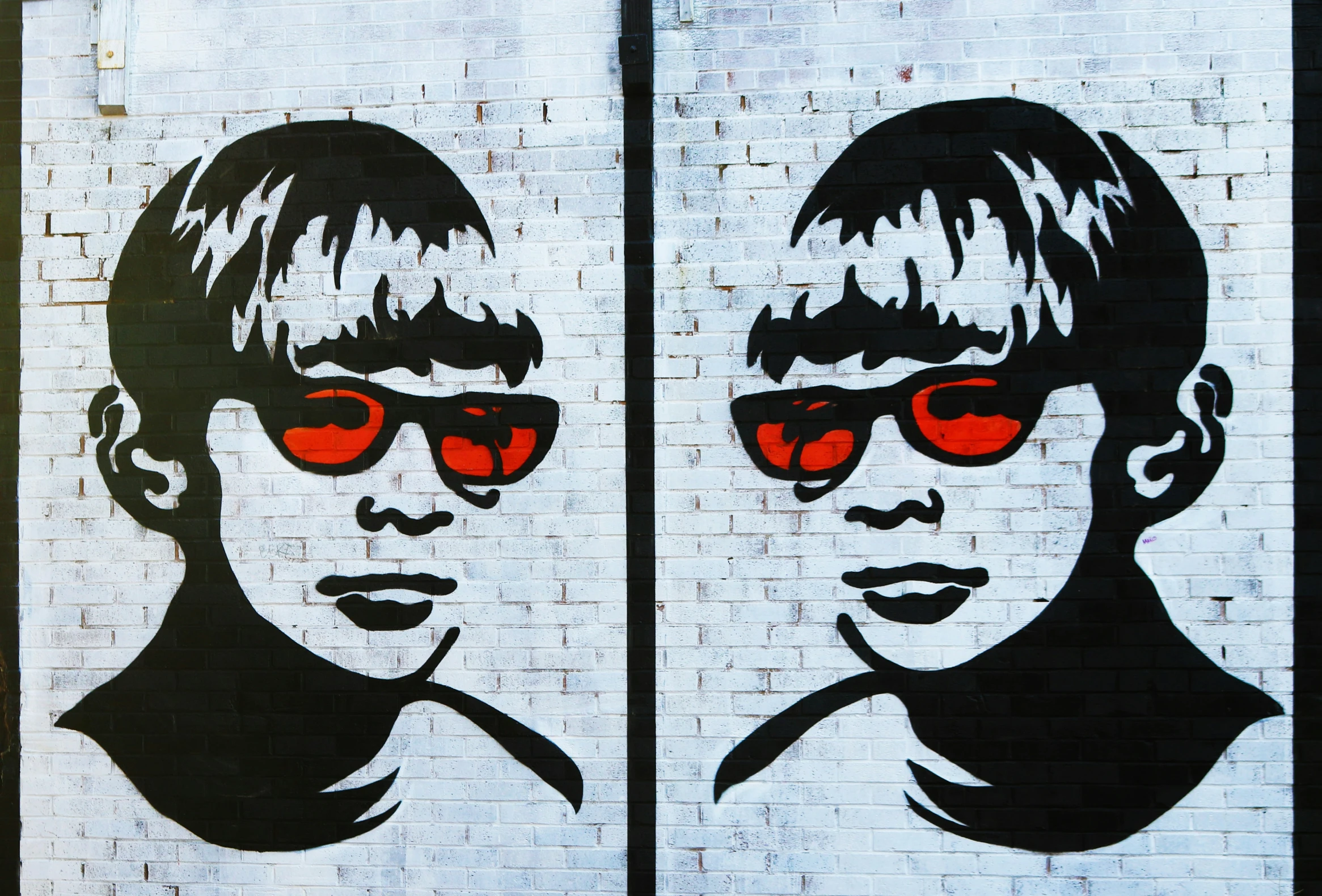 a painted wall shows two children with red sunglasses