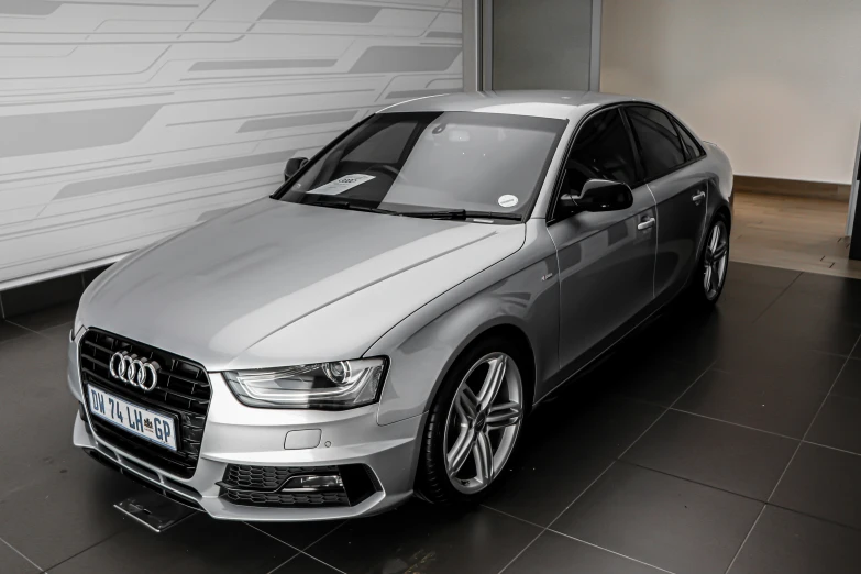 a silver car sits parked near a white wall