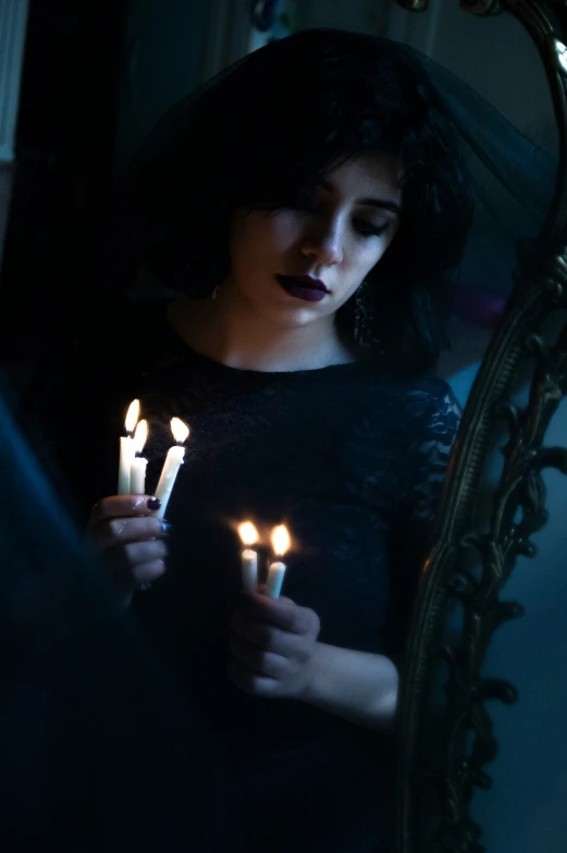 woman standing in front of a mirror with lit candles