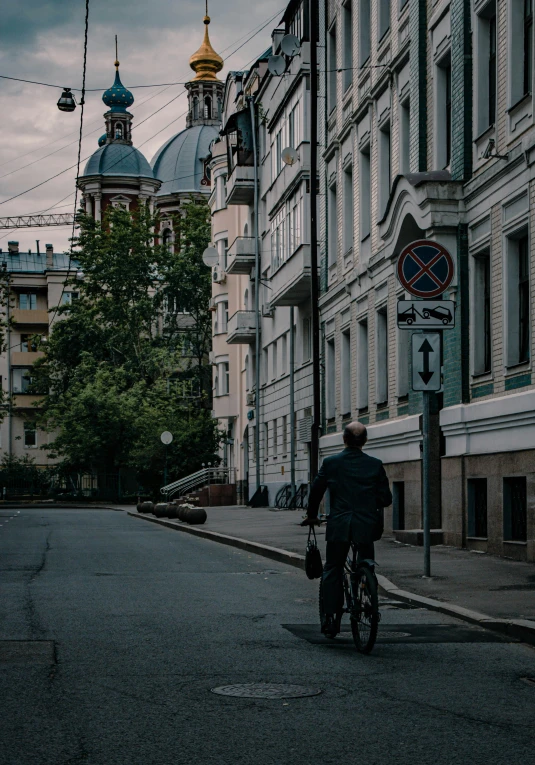 a man riding a bike down a street next to tall buildings