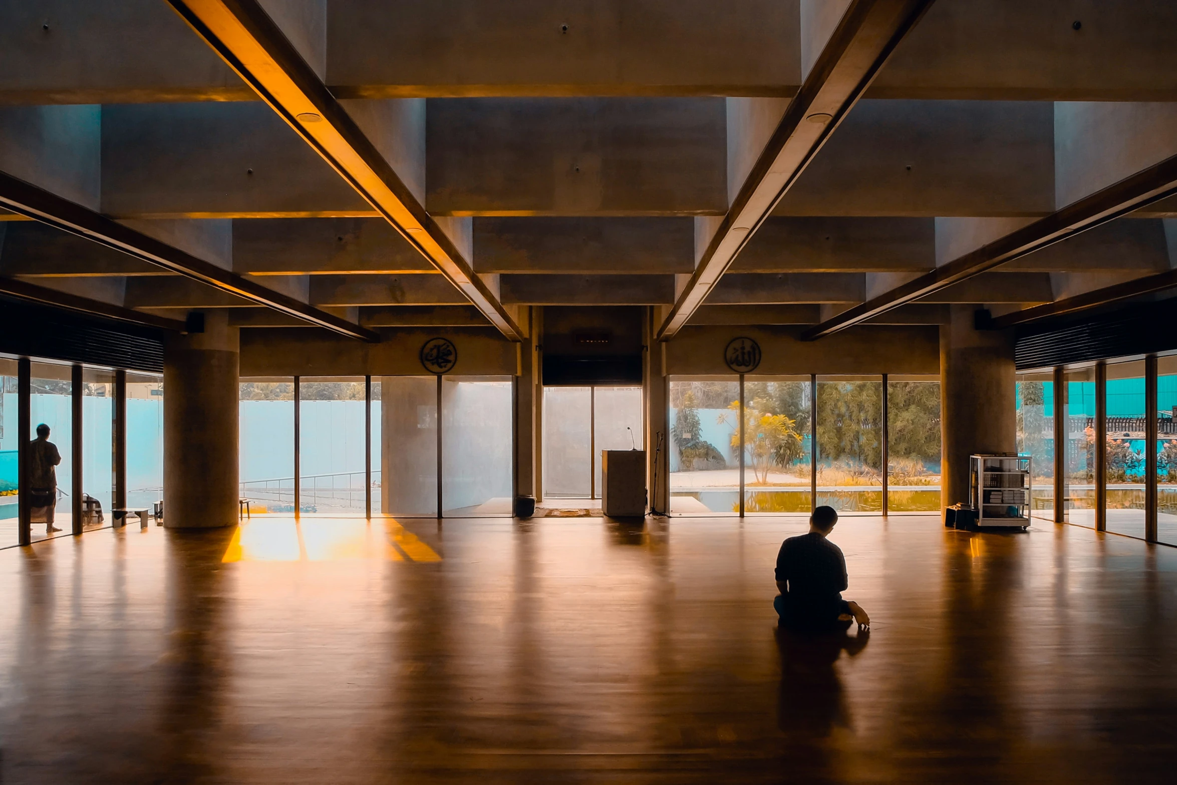 a person sits on the floor and looks out of a big room with huge doors