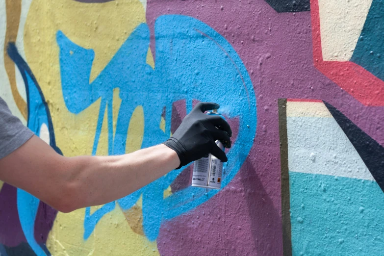 man spray painting graffiti on wall with spray bottle