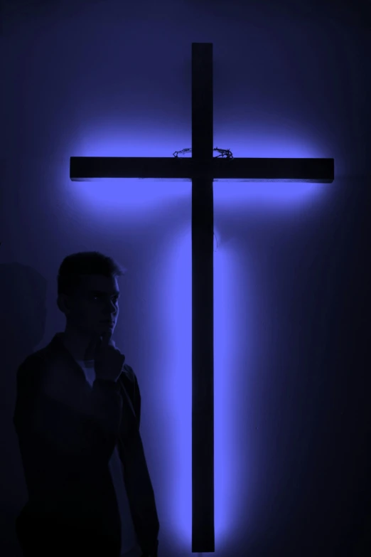 a person standing in front of a lit cross