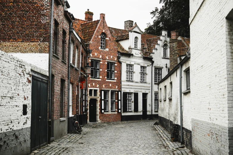 an old narrow street with two stone buildings and brickwork