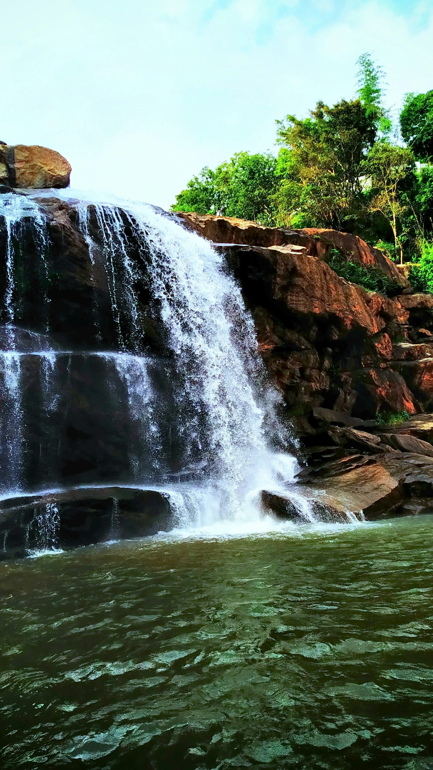 some people are swimming in the water under a large waterfall