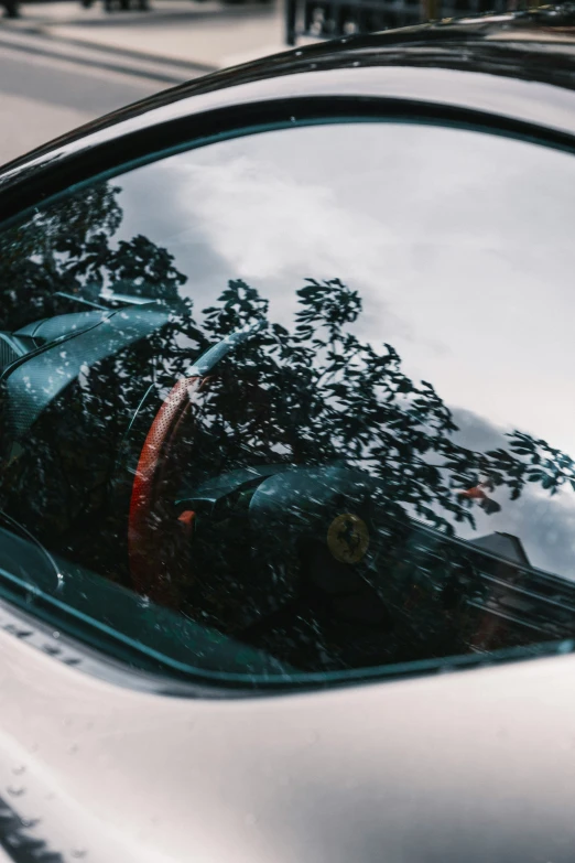 reflection in a car window of trees and a man in the mirror