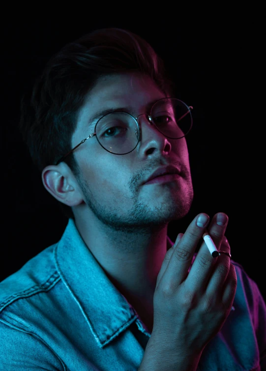 a man in glasses holding a cigarette in his hand