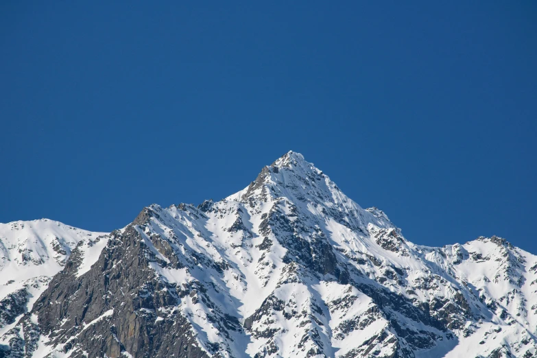 a snow covered mountain side with the sky in the background