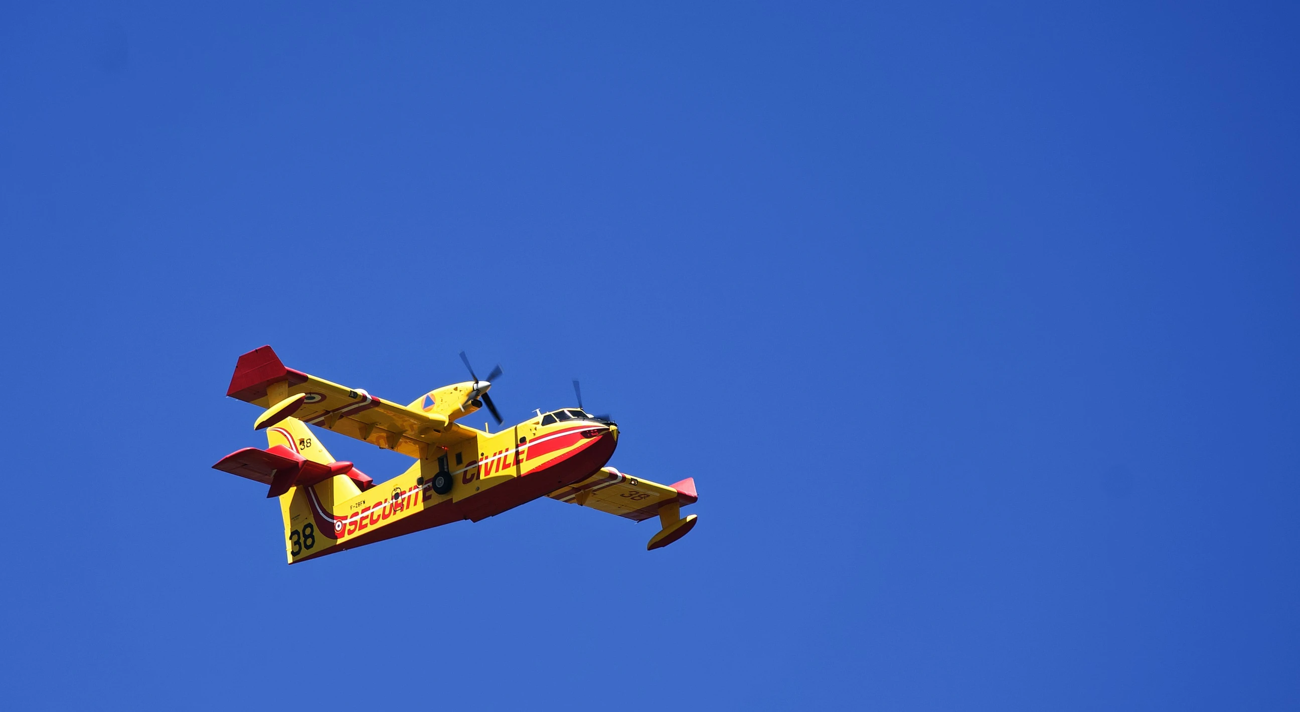 an old style plane flying across the blue sky