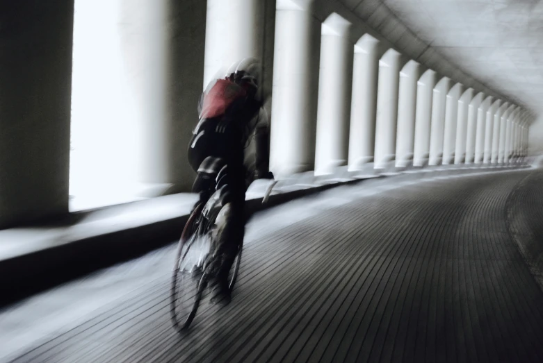 a person riding a bike past tall white columns