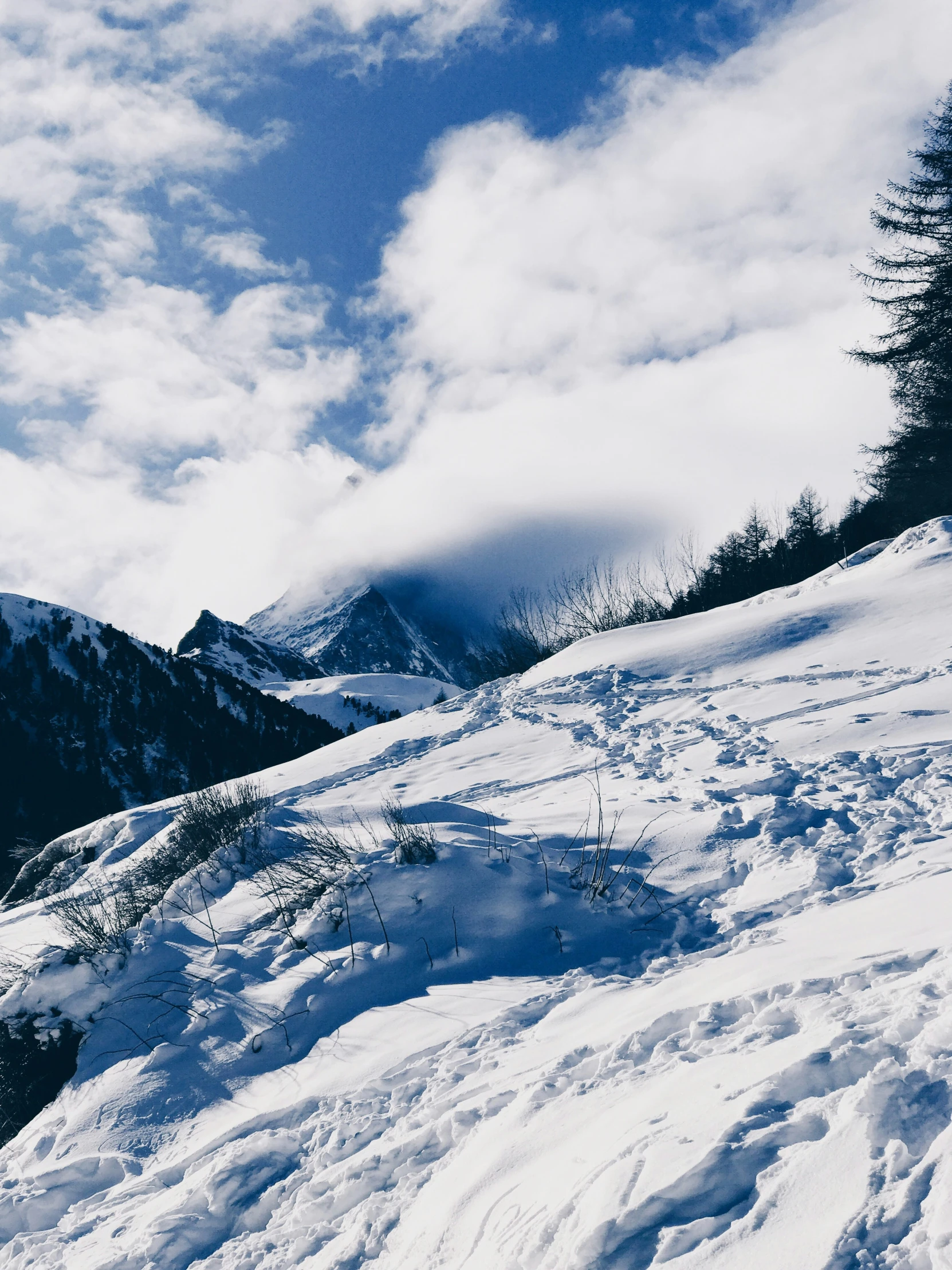 a snowy mountain slope with clouds in the distance