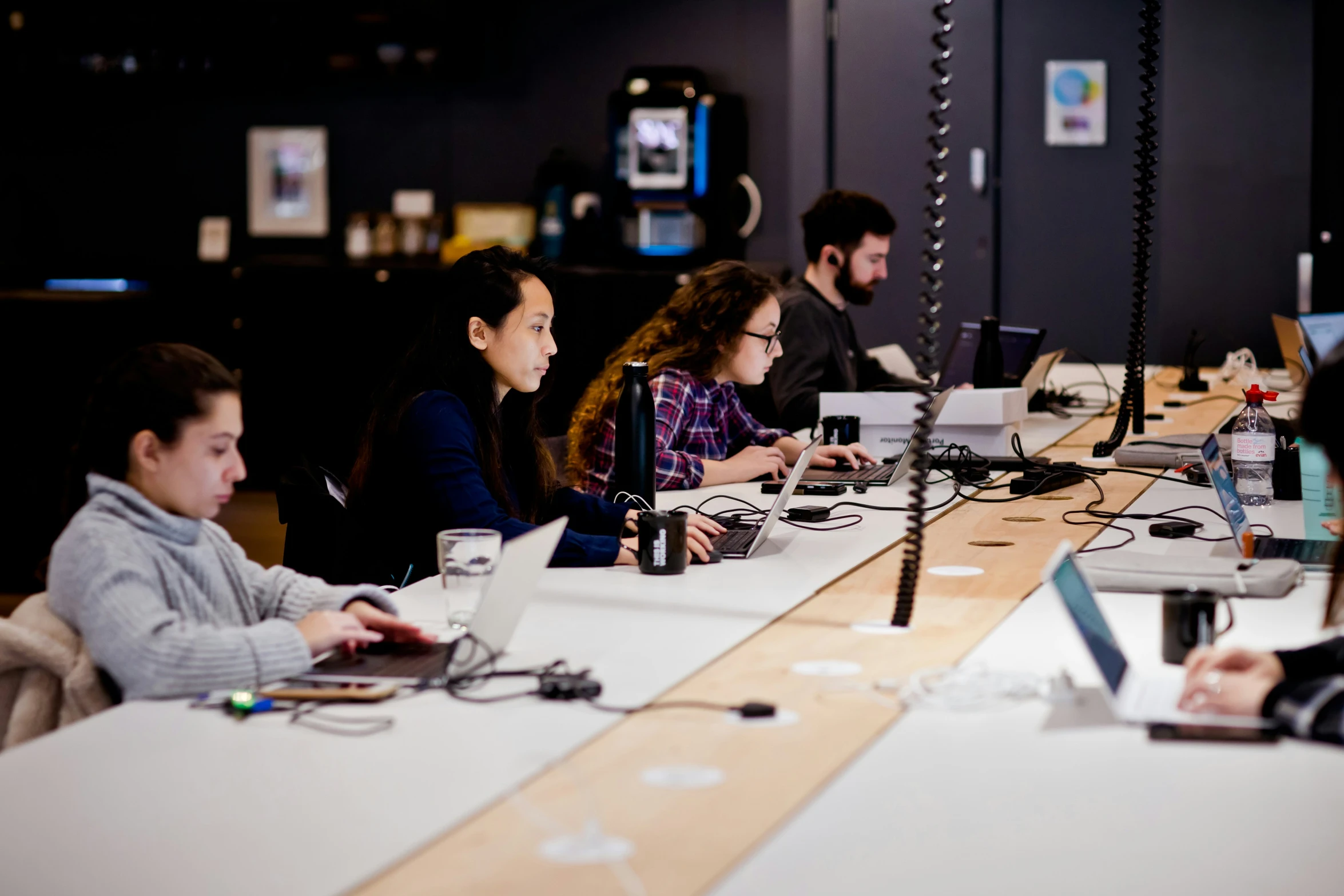 four people working with laptops in an open area