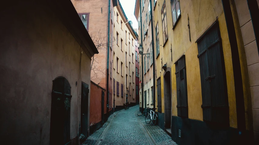 an alley way with tall buildings and cobblestone