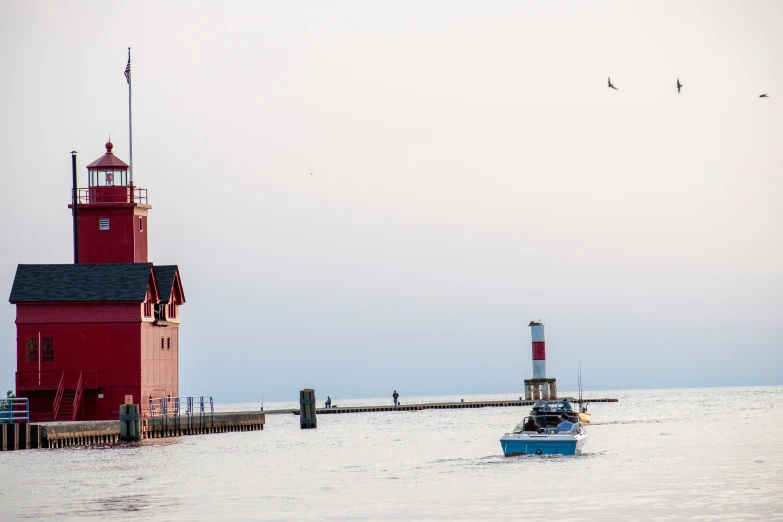 a small red and white lighthouse in the ocean next to a long dock