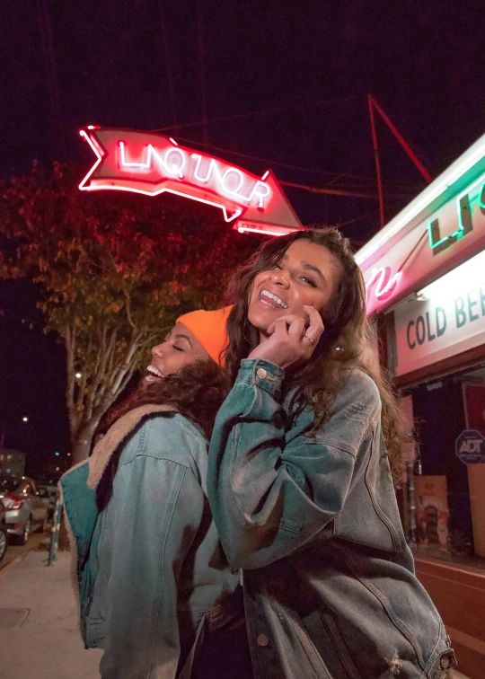 two women posing outside for the camera outside of a neon restaurant