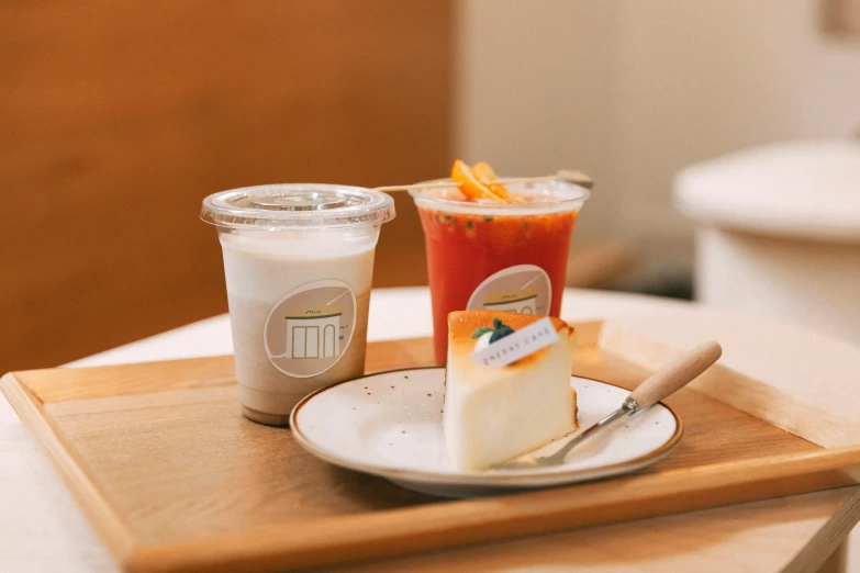 the breakfast table features a cup of orange juice, a slice of cake and a coffee on the tray