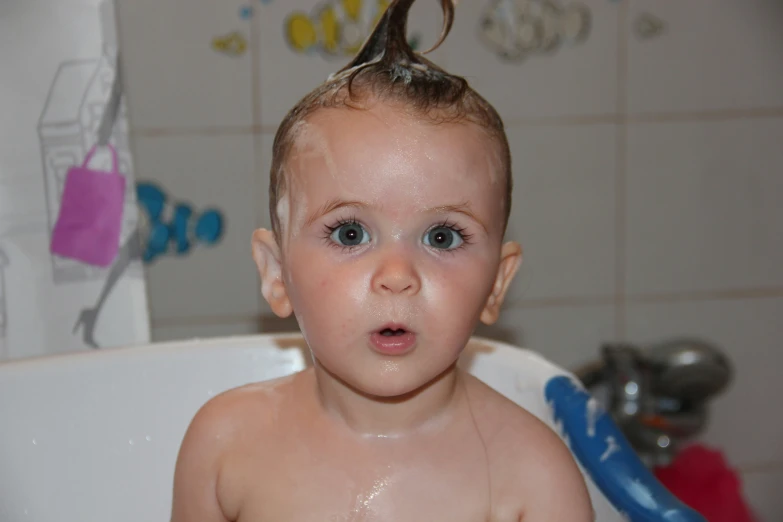 a baby sitting in the bathroom while it is raining