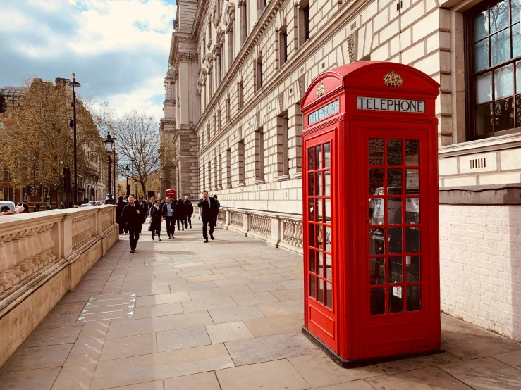 there are people walking near this telephone booth