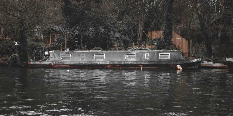 the barge is docked in a wooded river