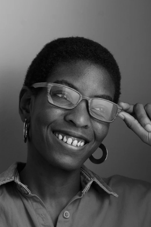 a woman wearing glasses and a shirt with silver rims smiles