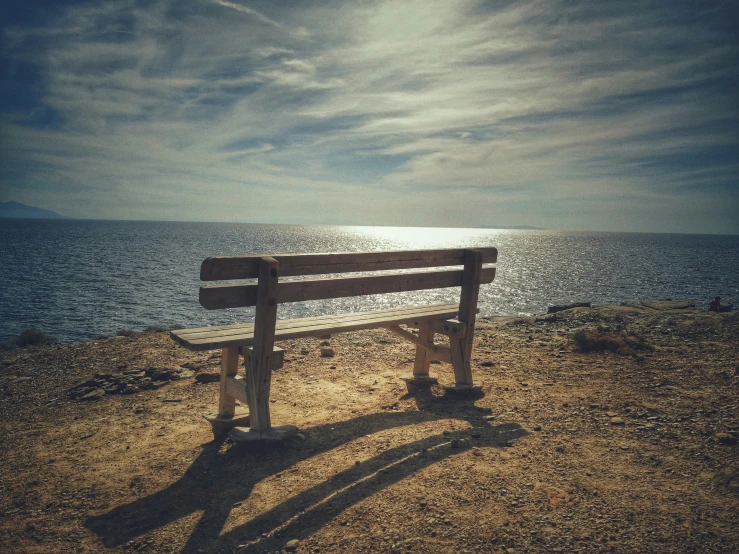 a wood bench is facing the water