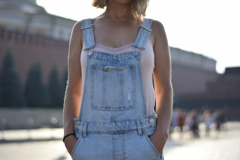 a woman in overalls and a hat on the street