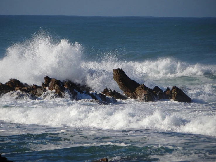 there is rough waves hitting the rocks in the water