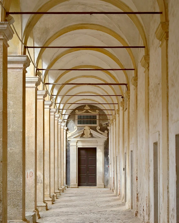 an empty, hallway in the middle of some columns and arches