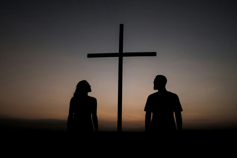 a cross sitting above two people near the sun