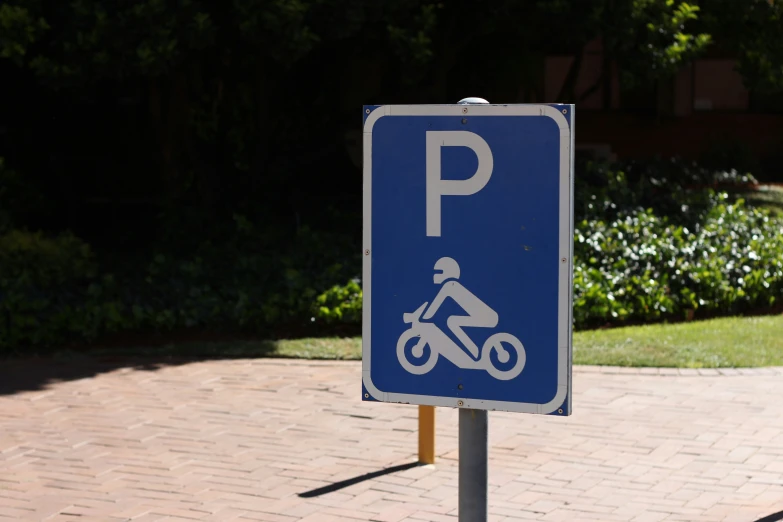 a blue parking sign on the street with trees in background