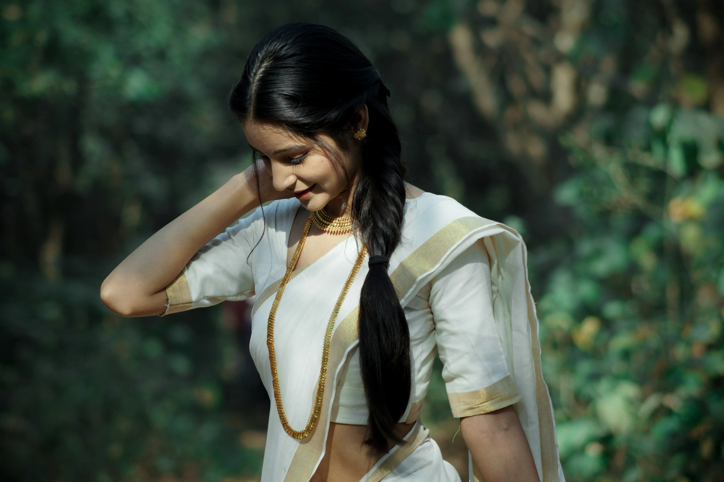 girl standing in front of a forest looking back with a long id in her hand