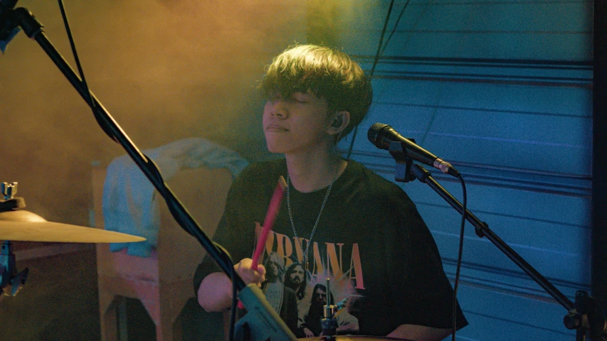 a man sitting next to a microphone and guitar